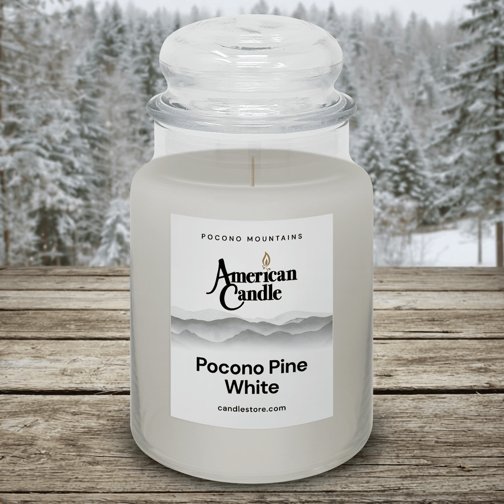 American Candle Pocono Pine White scented jar candle on a wooden table with a snowy pocono pines forest trees background