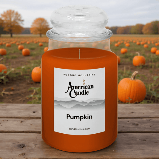American Candle Pumpkin jar scented candle with a pumpkin field in the background on wooden table