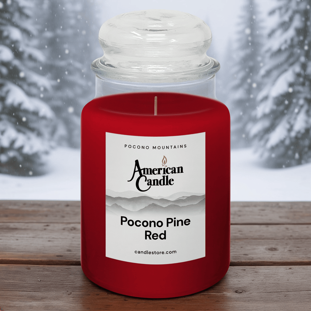 American Candle Pocono Pine Red Scented Jar Candle on a Wooden Table in front of the Wintery Pine Trees