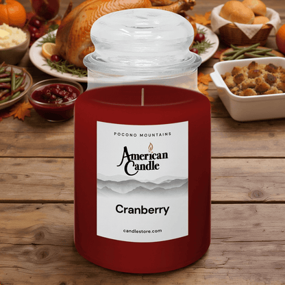 American Candle Cranberry Scented Jar Candle on Wooden Table in front of a Thanksgiving Dinner