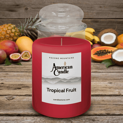 American Candle Tropical Fruit Scented Jar Candle on a Wooden Table with Tropical Fruits on the Table