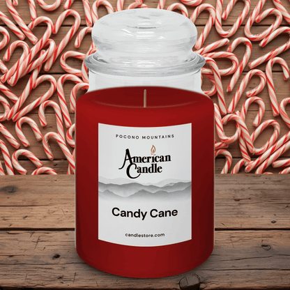 American Candle Candy Cane scented Jar Candle on a wooden surface with candy canes in the background.