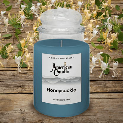 American Candle Honeysuckle Scented Jar Candle on a wooden table with Honeysuckle flowers in the background