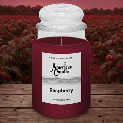 American Candle Raspberry jar scented candle on wooden table with raspberry field background