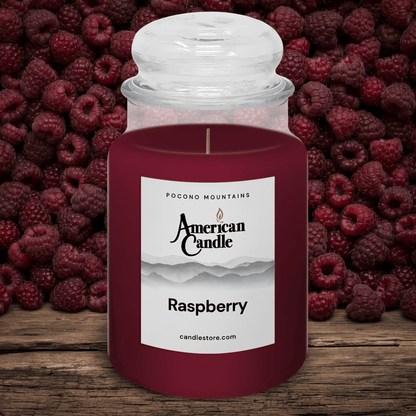 American Candle with raspberry scented jar candle in front of raspberries on a wooden table